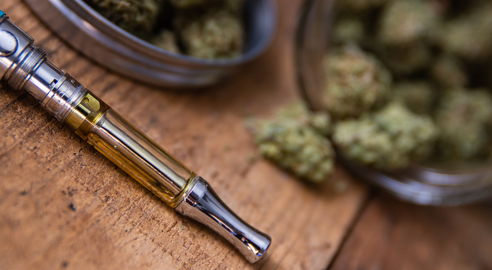 Cannabis Oil Vape Pen & Marijuana Buds In Open Glass Jar In Background Cannabis Oil Vape Pen