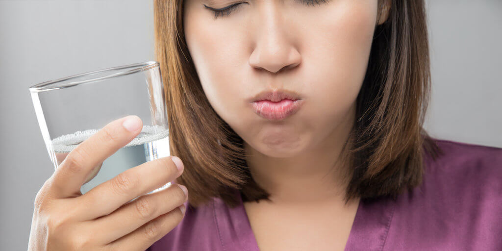 Woman rinsing and gargling while using mouthwash from a glass, During daily oral hygiene routine, Girl in a purple silk robe, Dental Healthcare Concepts Woman rinsing and gargling