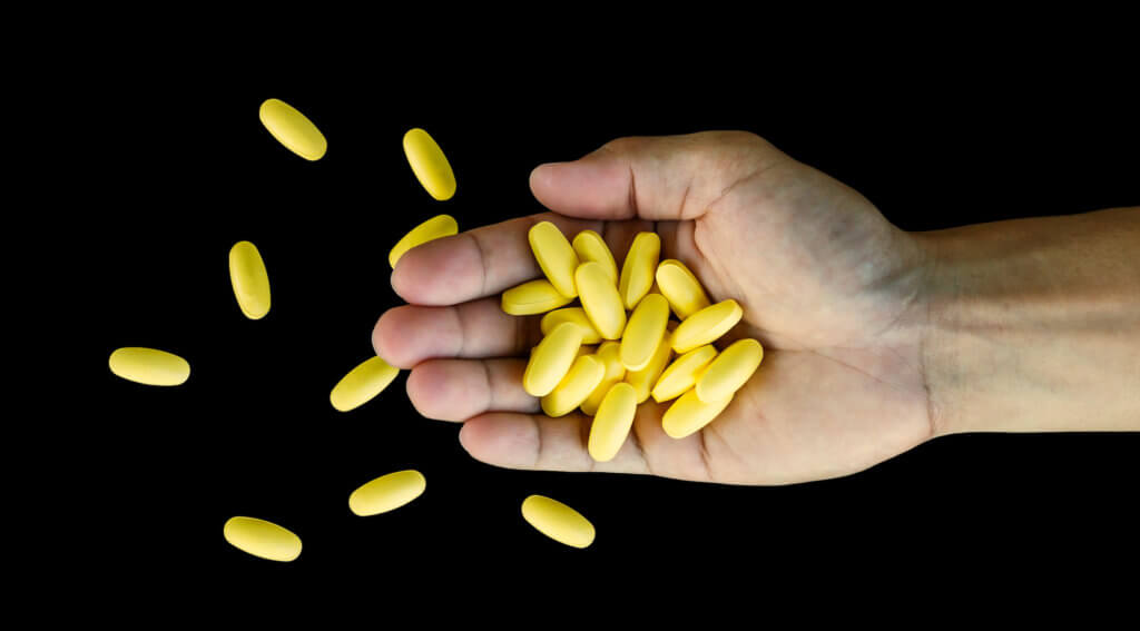 man holding a bunch of drugs in his hand. man holding a bunch of drugs in his hand, on a black background.