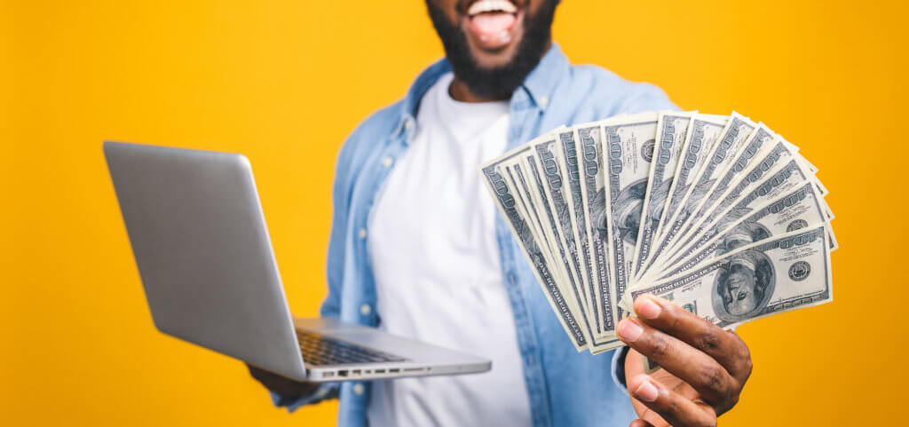 Photo of a happy young afro american handsome man posing isolated over yellow wall background using laptop computer holding money. Photo of a happy young afro american handsome man posing isolated over yellow wall background using laptop computer holding money.